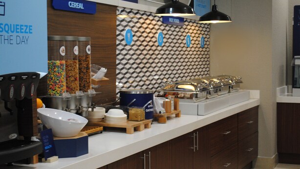 Un buffet pour le petit-déjeuner proposant des céréales, des fruits et différentes sortes de café.
