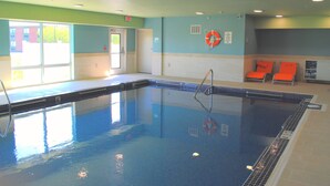 Une piscine intérieure à l’eau claire, équipée d’une bouée de sauvetage et d’un panneau indiquant une profondeur de 4 mètres.