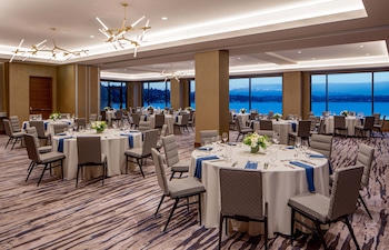 A modern kitchen with a central island, bar stools, a coffee machine, and a view of a body of water. at Hyatt Regency Lake Washington at Seattle