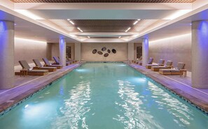 Relax by the pool surrounded by lounge chairs and circular mirrors.