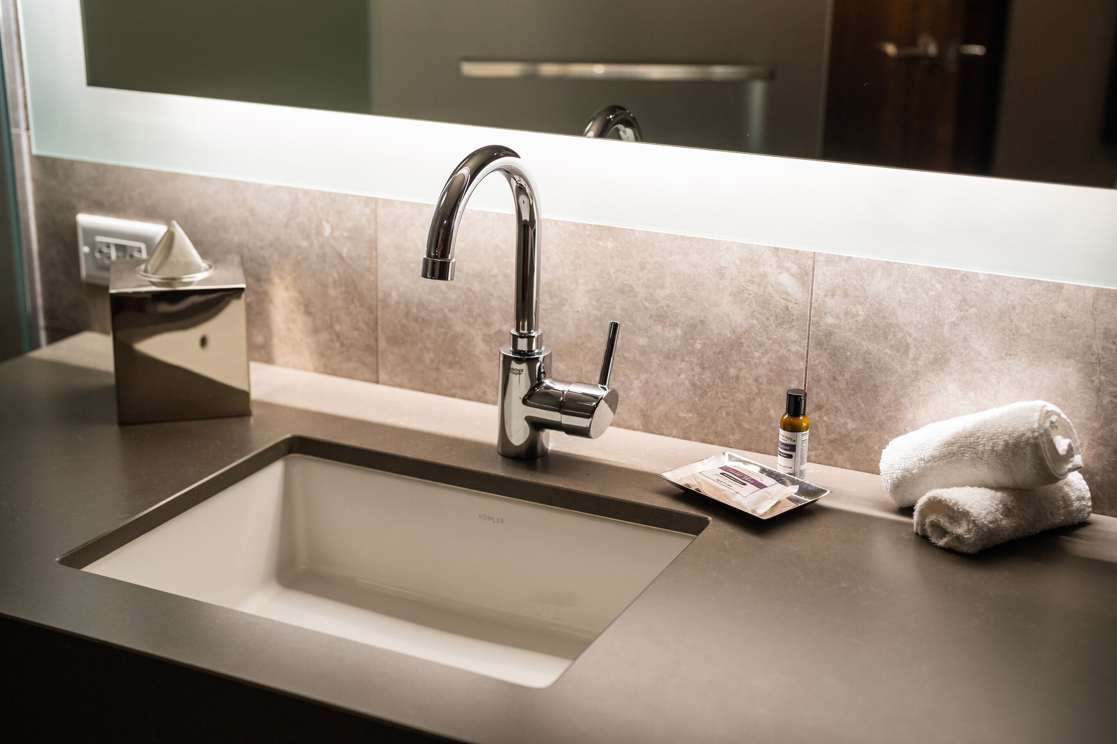 Un baño moderno con un lavamanos grande, un espejo y un perchero para toallas.