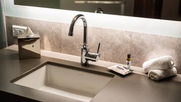 Un baño moderno con un lavamanos grande, un espejo y un perchero para toallas.