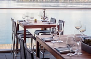 A dining table with chairs and wine glasses, overlooking a body of water. - Hyatt Regency Lake Washington at Seattle’s Southport (Renton)