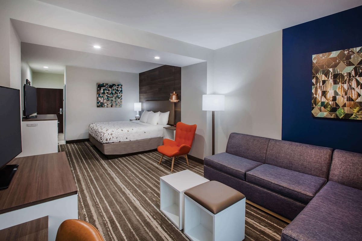 Una habitación de hotel moderna con cama, sofá, escritorio y televisor.