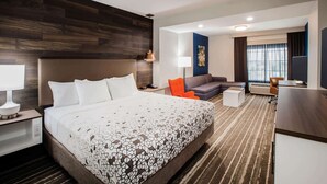 A hotel room with a large bed, a sofa, a desk, and a window with curtains. - La Quinta Inn & Suites by Wyndham Owasso (Owasso)