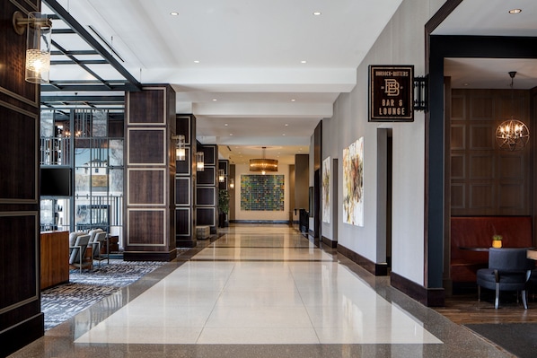 Un moderno vestíbulo de hotel con piso pulido, un mostrador de recepción y una zona de bar/lounge.