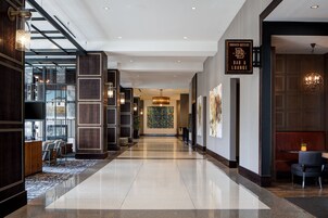 Un moderno vestíbulo de hotel con piso pulido, un mostrador de recepción y una zona de bar/lounge.