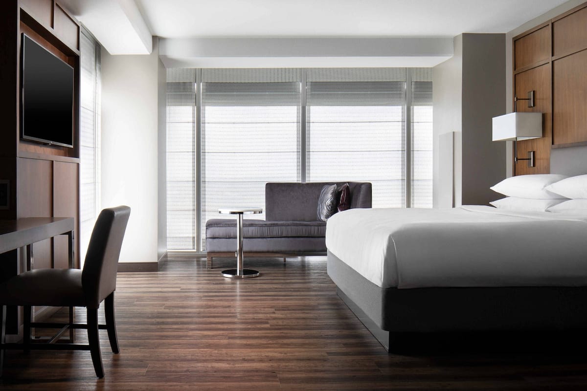 Una habitación de hotel con cama, escritorio, silla y televisor.