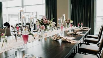 A long dining table set with floral centerpieces, candles, and glasses.