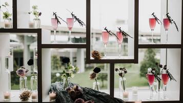 Une pièce dotée de nombreuses fenêtres, chacune présentant une composition différente de vases, de fleurs et de bougies.