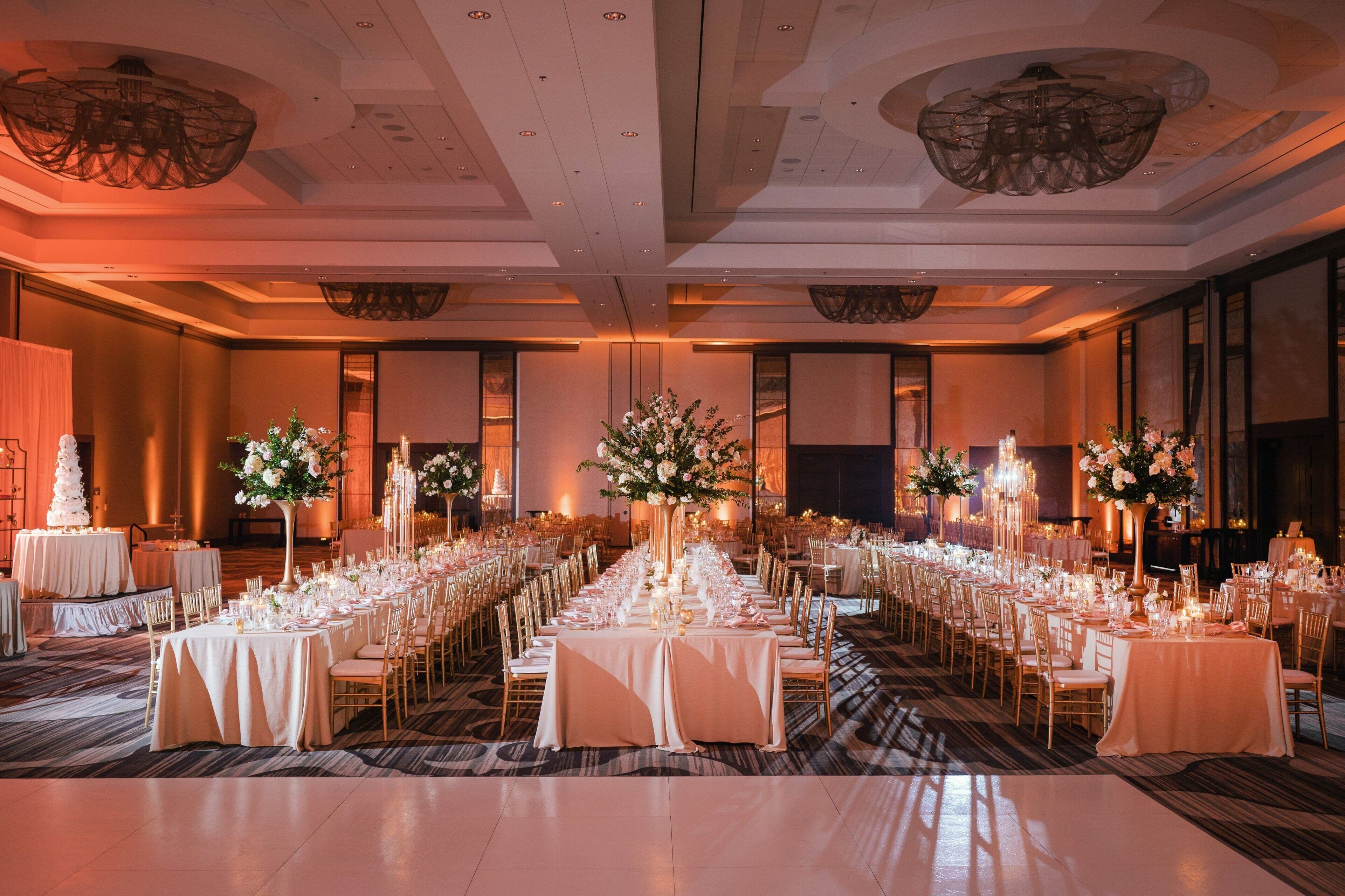 A banquet hall with long tables set for a formal event, featuring floral centerpieces and elegant table settings.