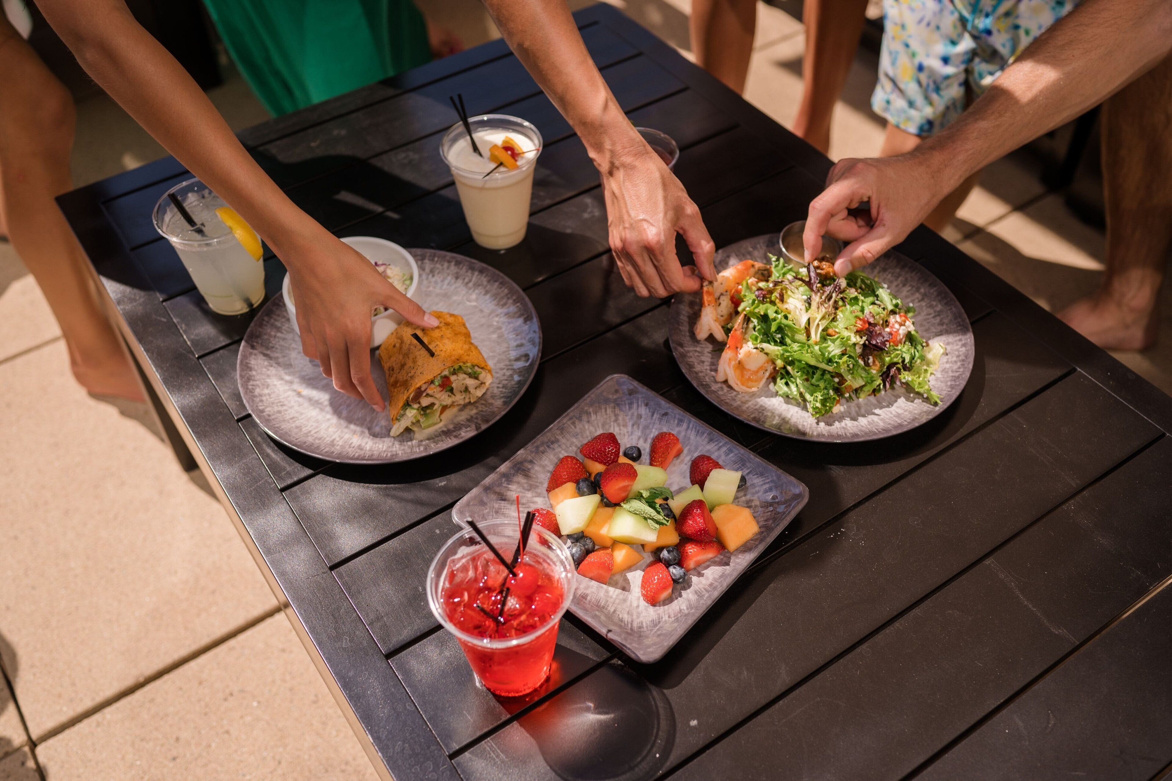 A table with plates of food, drinks, and a fruit platter.