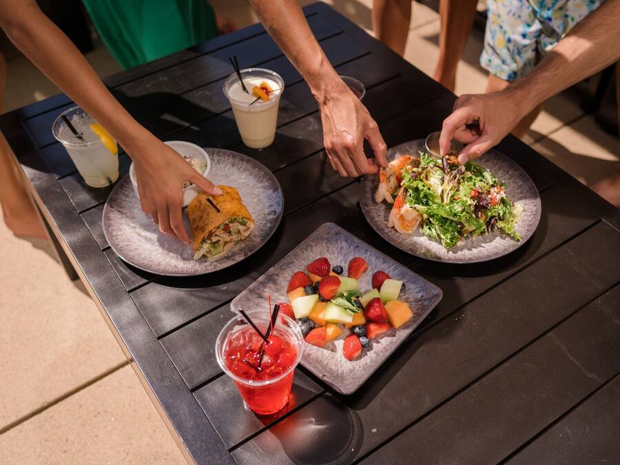 A table with plates of food, drinks, and a fruit platter.