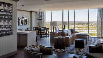 Panoramic views of a body of water and distant buildings can be enjoyed from the large window in this living area.