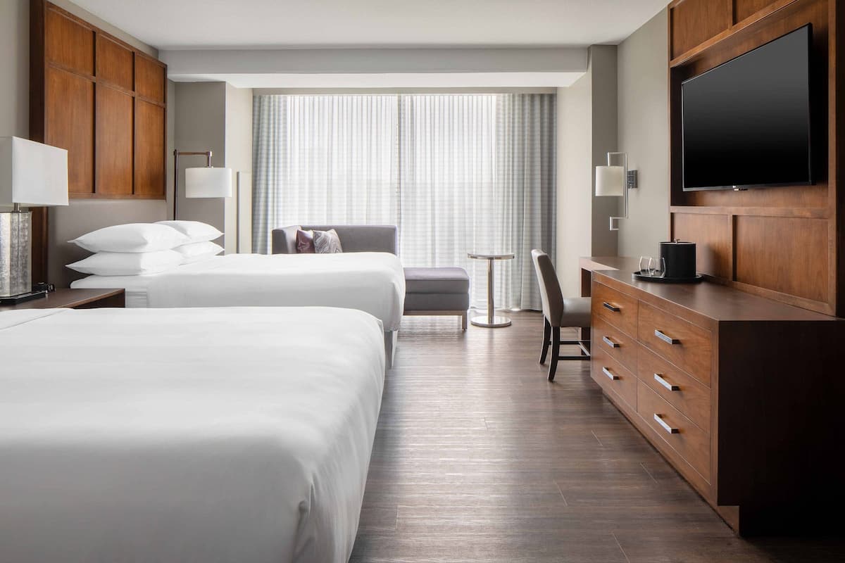 Habitación de hotel con dos camas, televisión, escritorio y silla.