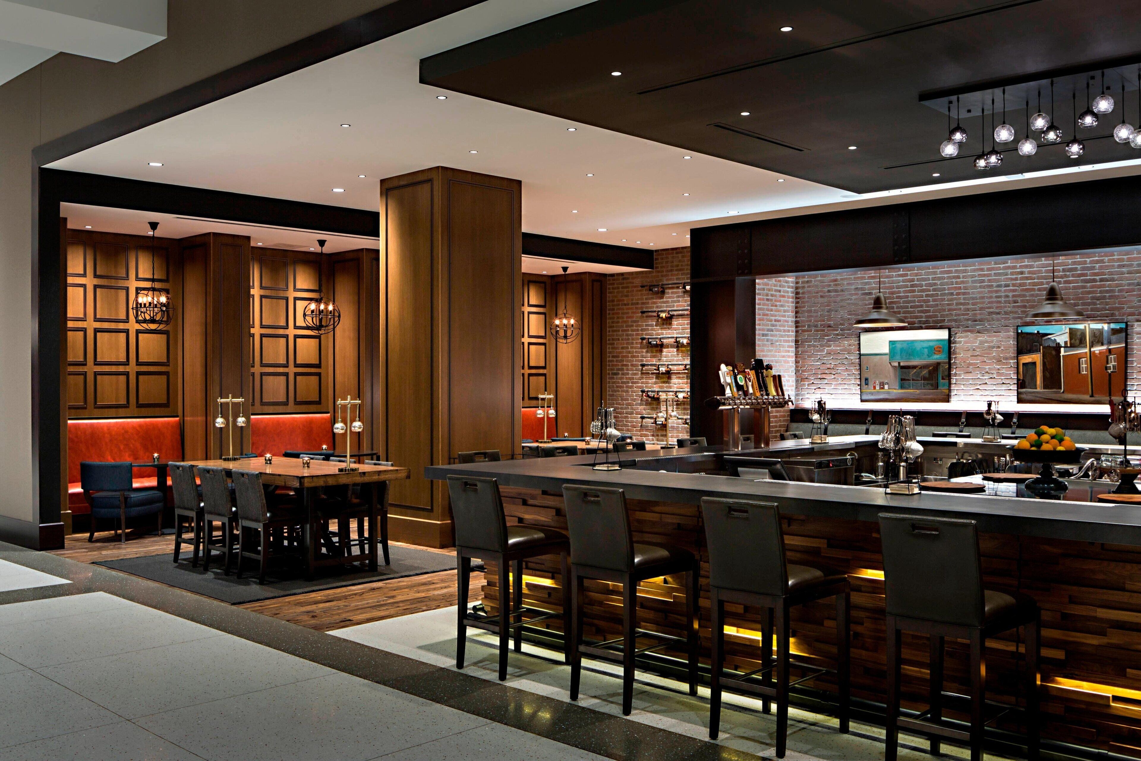 Cozinha moderna com ilha central, banquetas e área de jantar com mesa e cadeiras.