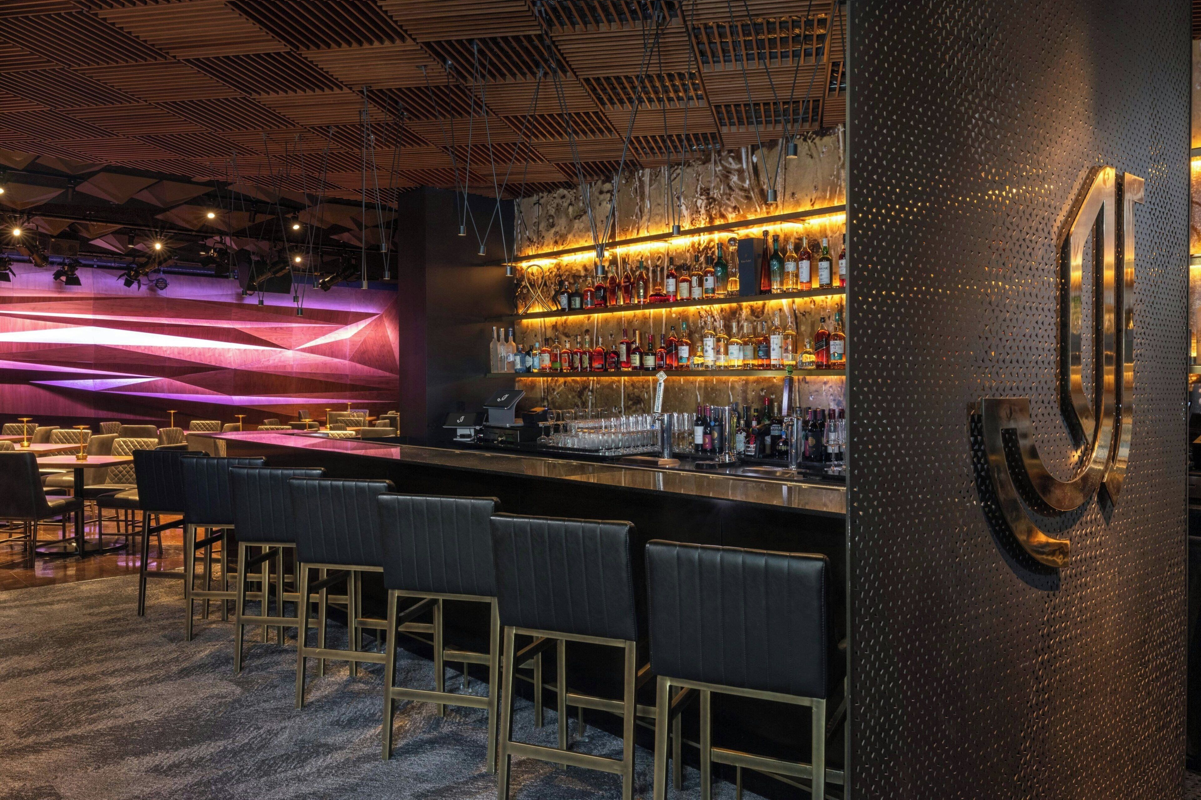 Un espace bar au design moderne, comprenant un comptoir, des sièges et un mur décoratif.