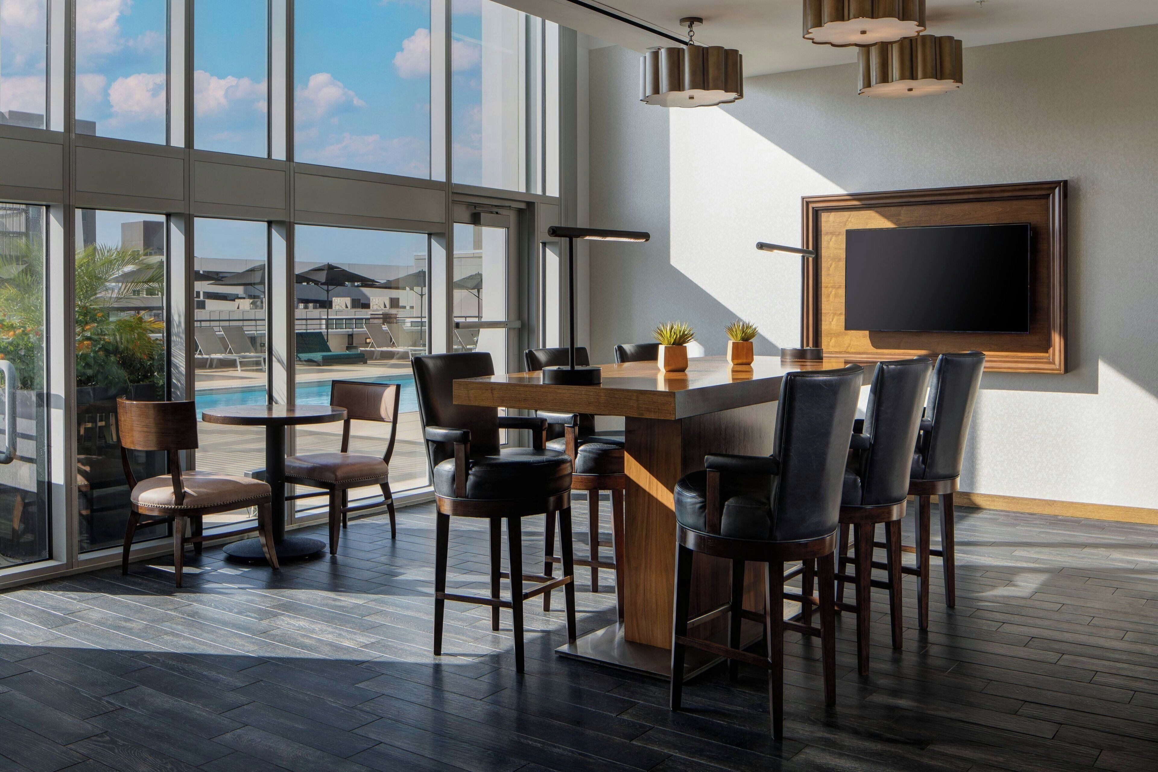 A modern bar area with a pool view, large windows, and a flat-screen TV.