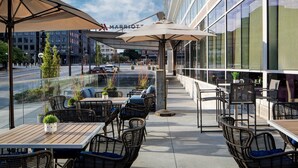 Eine Außenpatio-Terrasse mit Korbmöbeln, Sonnenschirmen und Topfpflanzen.