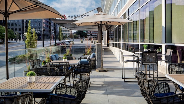 Un espace extérieur aménagé en terrasse, avec des meubles en osier, des parasols et des plantes en pot.