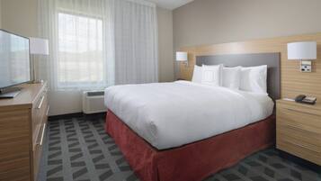 Habitación de hotel con una cama grande, dos lámparas de noche, televisión, escritorio y ventana con cortinas translúcidas.