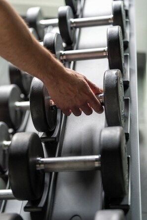 A hand adjusting a weight on a rack of dumbbells. - YOTEL Boston (Boston)