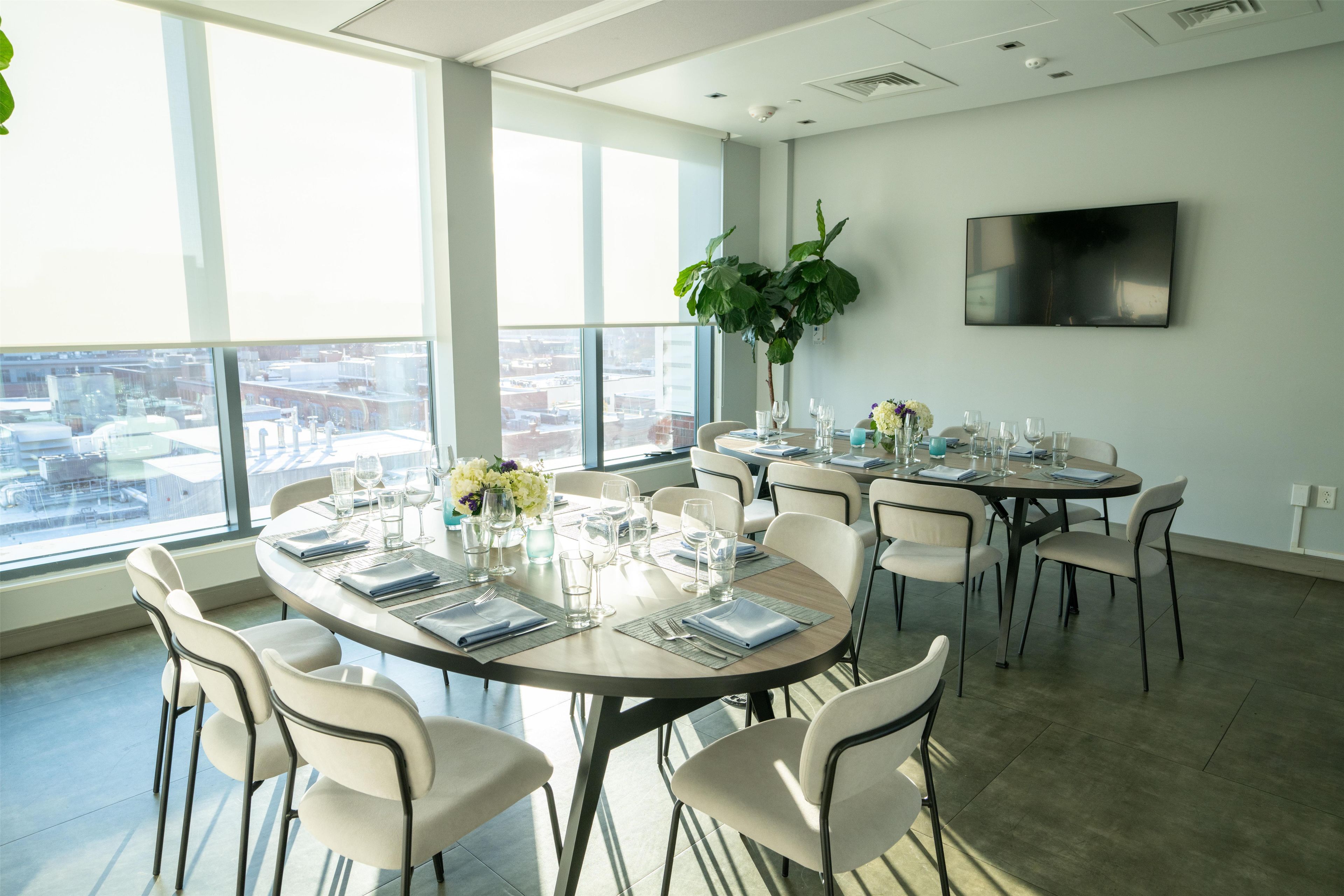 A conference room with round tables, chairs, and a large window with a city view.