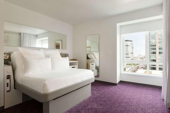 Relax in a stylish room with a large bed, bedside table, and city view.