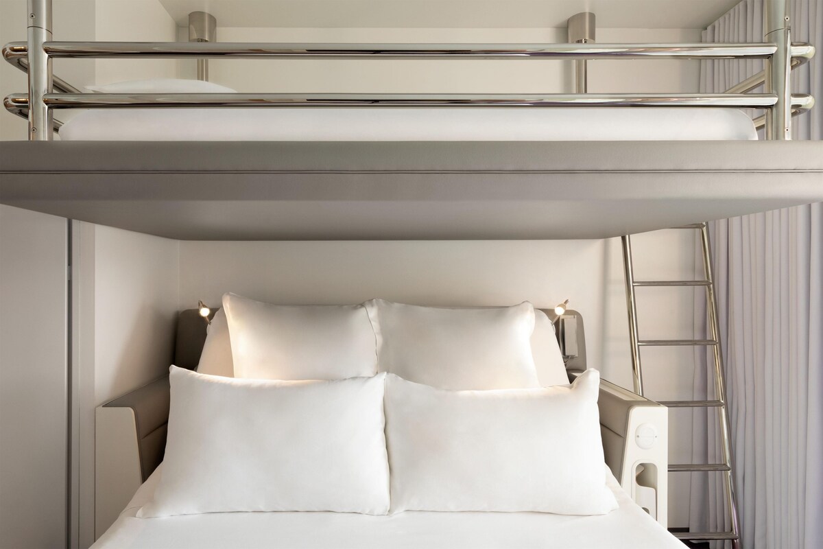A bunk bed with two pillows, a ladder, and a headboard.