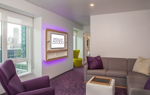 A modern hotel room with a large window, a sofa, a chair, and a TV mounted on the wall. - YOTEL Boston (Boston)