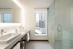 A modern bathroom with two sinks, a large mirror, and a glass shower enclosure.