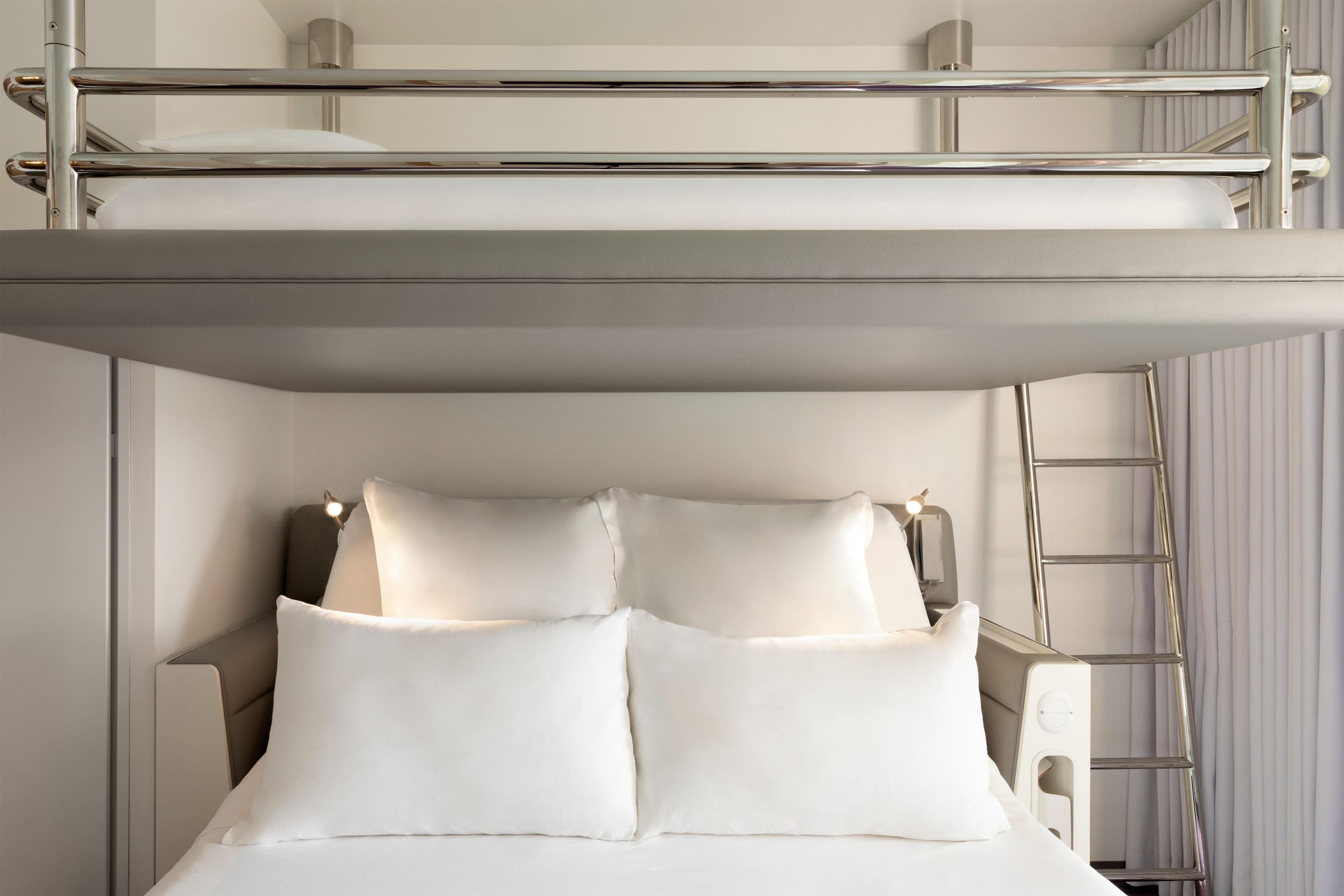 Una cama litera con dos almohadas, una escalera y un cabecero.