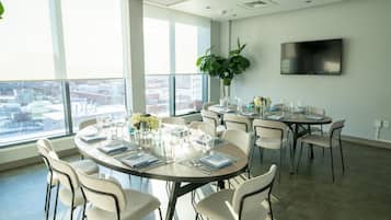 Un salón de conferencias con mesas redondas, sillas y un amplio ventanal con vista a la ciudad.