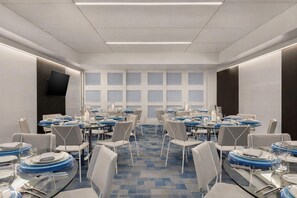 A conference room with multiple tables set for dining, equipped with chairs and tableware. - YOTEL Boston, Select by Hilton (Boston)