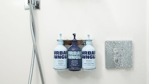 A shower with three bottles of Urban Jungle products: shampoo, conditioner, and hand & body wash. - YOTEL Boston, Select by Hilton (Boston)