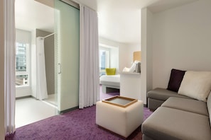 Enjoy a city view from the large window, relax on the sofa and ottoman, and sleep in comfort on the bed with a white headboard.