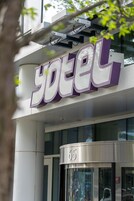 A szálloda bejárata, amelyen feltűnően nagy „yotel” felirat látható, és egy forgóajtó vezet be, melyen a „65” szám szerepel.