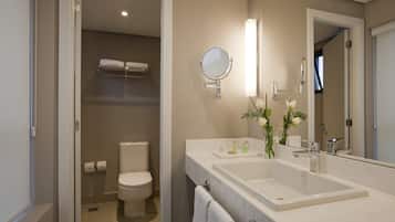 Un baño moderno con inodoro, dos lavamanos, un espejo y un perchero para toallas.