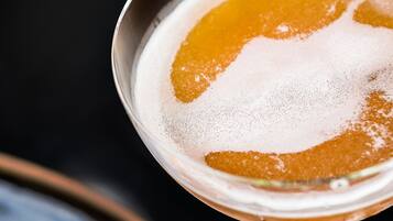 Un cóctel en una copa de martini con una decoración floral, sobre un fondo oscuro.