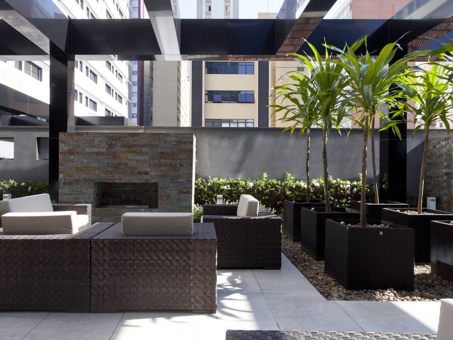 An outdoor seating area with wicker furniture and a stone fireplace.