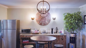 A kitchen with a stainless steel refrigerator, a microwave, a wooden clock, a round table with chairs, a water dispenser, and a potted plant. - Allenberry Resort (Boiling Springs)