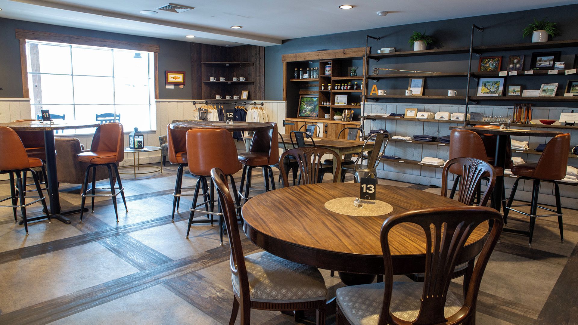 Un restaurant doté d’une grande table ronde au centre, de plusieurs tabourets de bar et d’un espace salon avec des chaises.