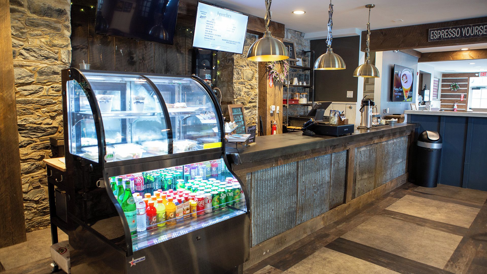 A self-service beverage station with a variety of drinks, a coffee machine, and a menu board above it.