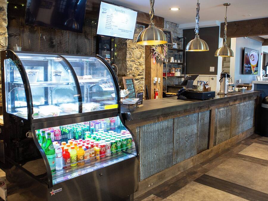 Una estación de autoservicio para bebidas con diversas opciones, una máquina de café y un cartel con el menú.