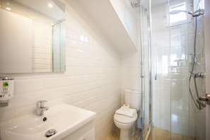 A modern bathroom with a white sink, toilet, and glass shower enclosure.