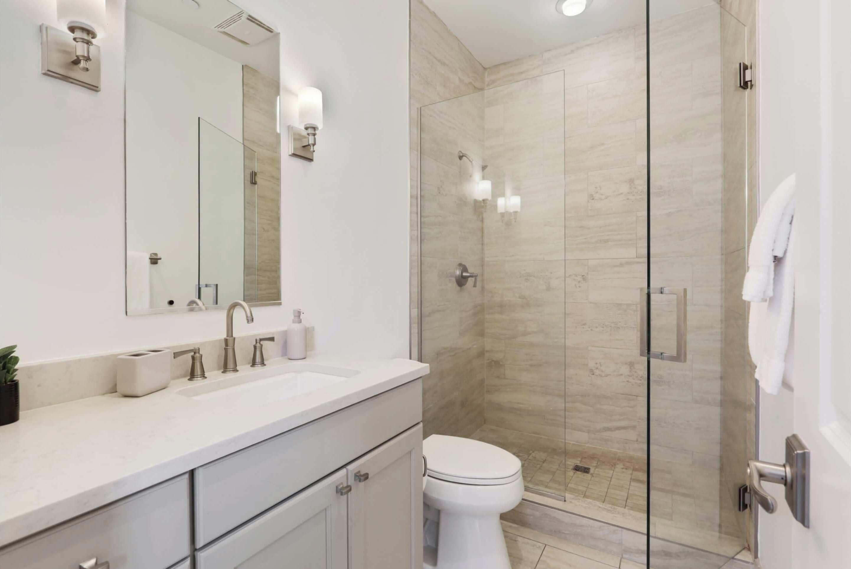 A modern bathroom with a glass-enclosed shower, a white sink, and a toilet.