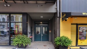 L'ingresso di un edificio con porte doppie, un neon che pubblicizza un ristorante di pesce e piante in vaso.