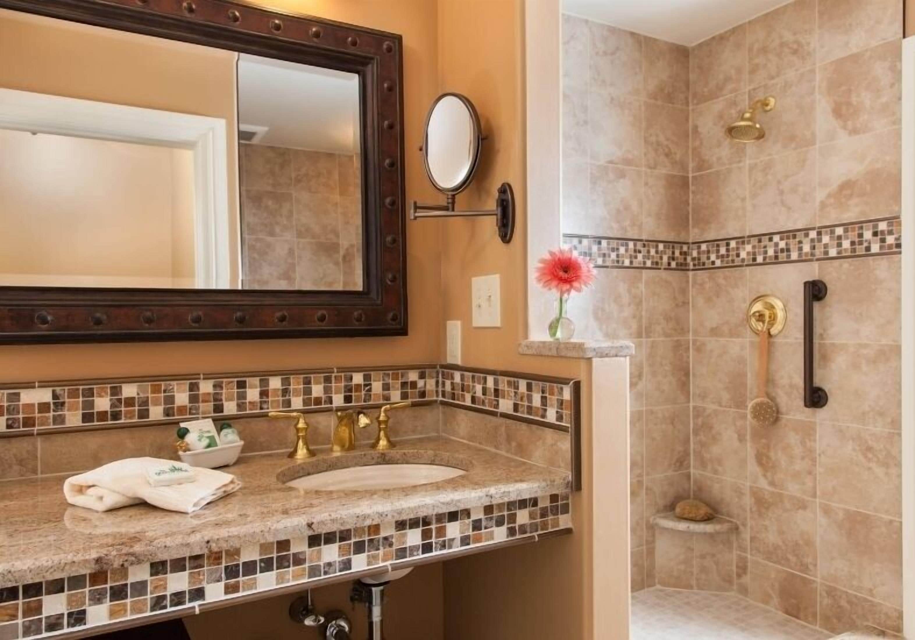 A bathroom with a marble sink, a large mirror, and a shower area.