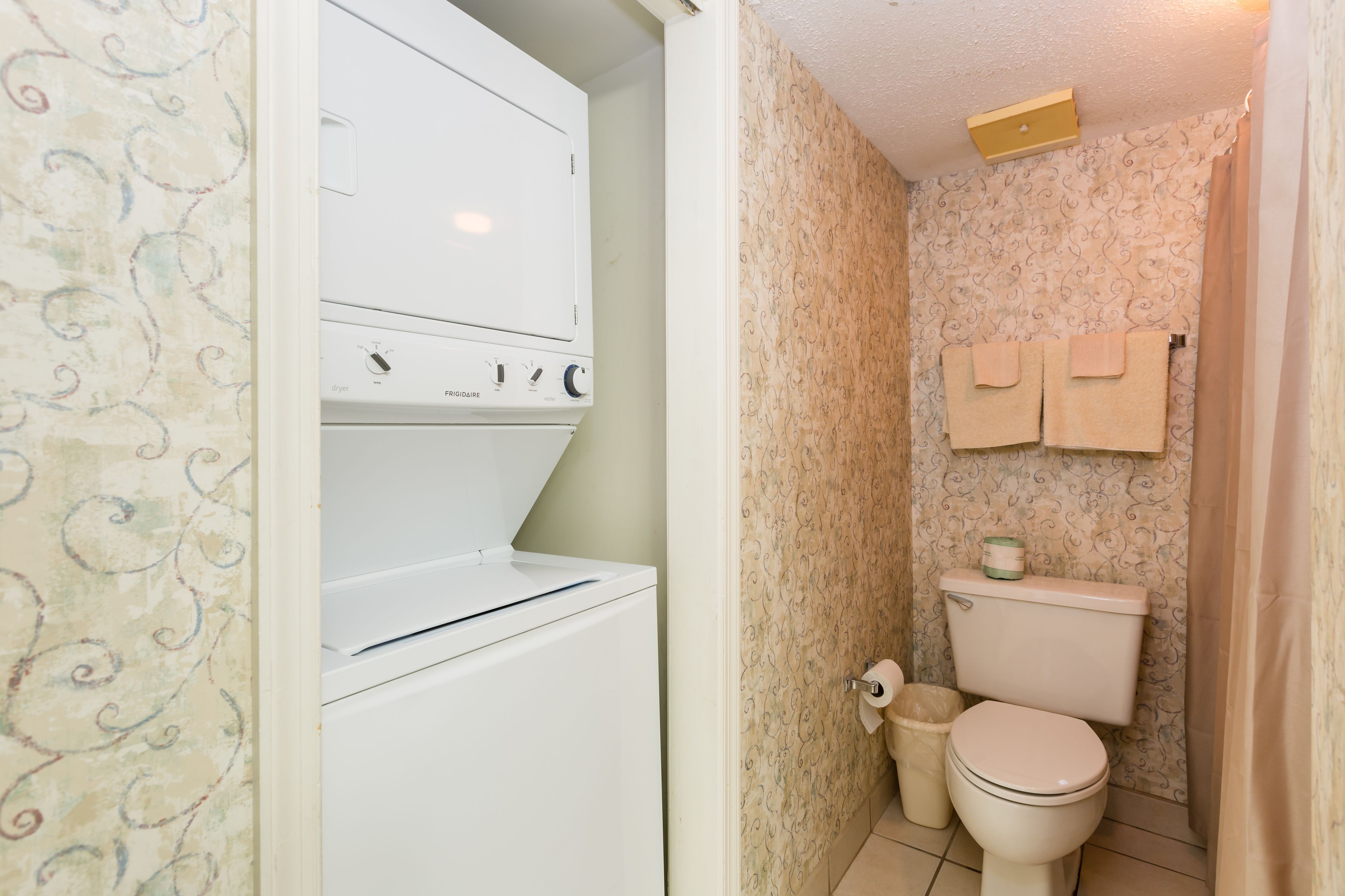Un baño pequeño con inodoro, un cubo de basura y un perchero de pared.