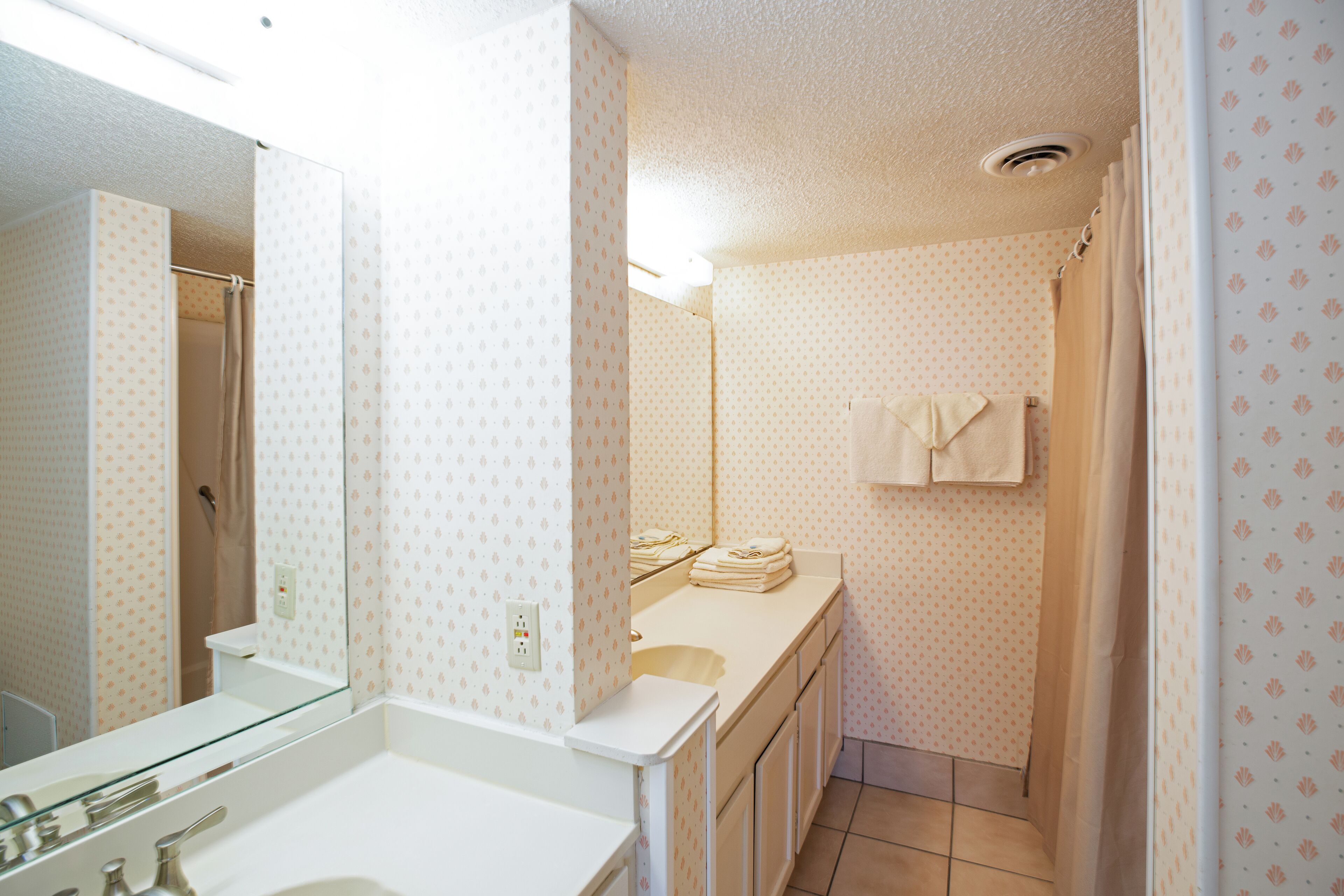 A bathroom with a white sink, a mirror, and a shower area.